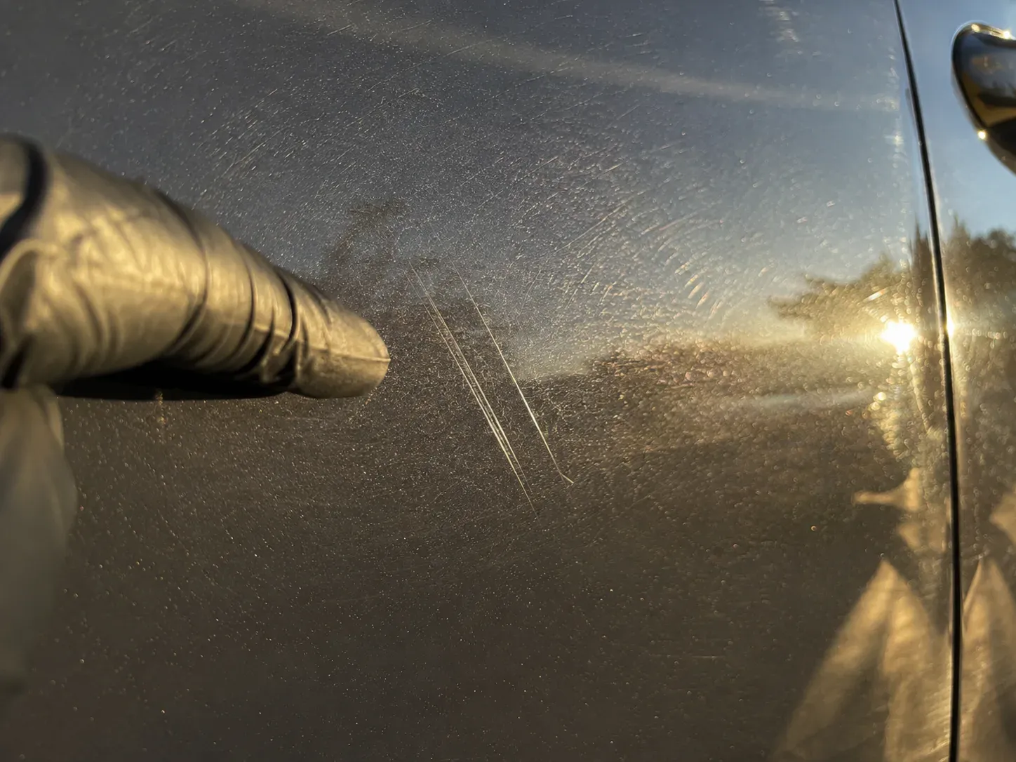 Detailer inspecting deep paint scratches beyond clay bar treatment scope